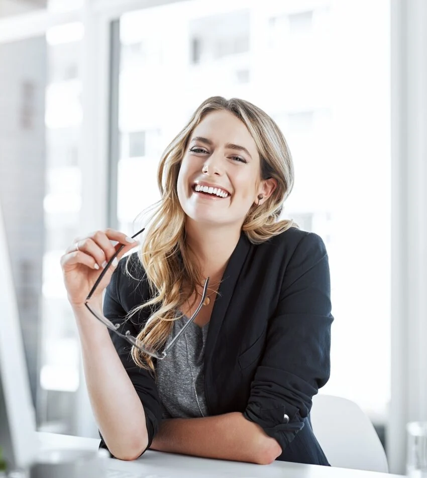 Avery Hale laughing in her office, glasses in hand