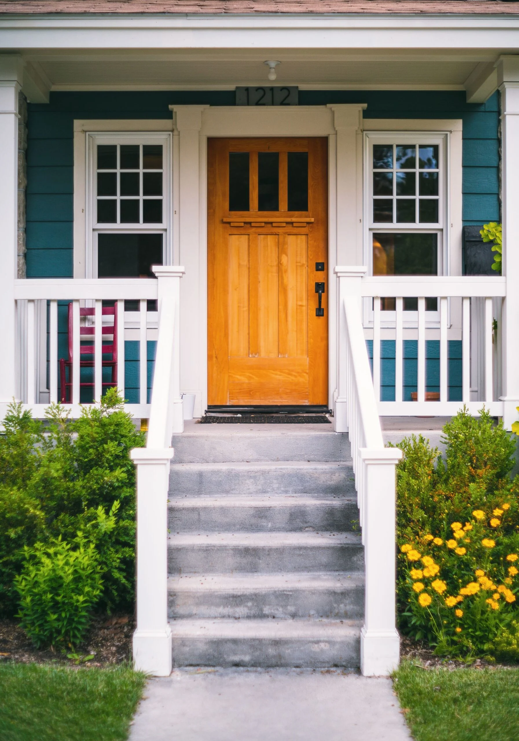 Porch steps up to a bright yellow front door